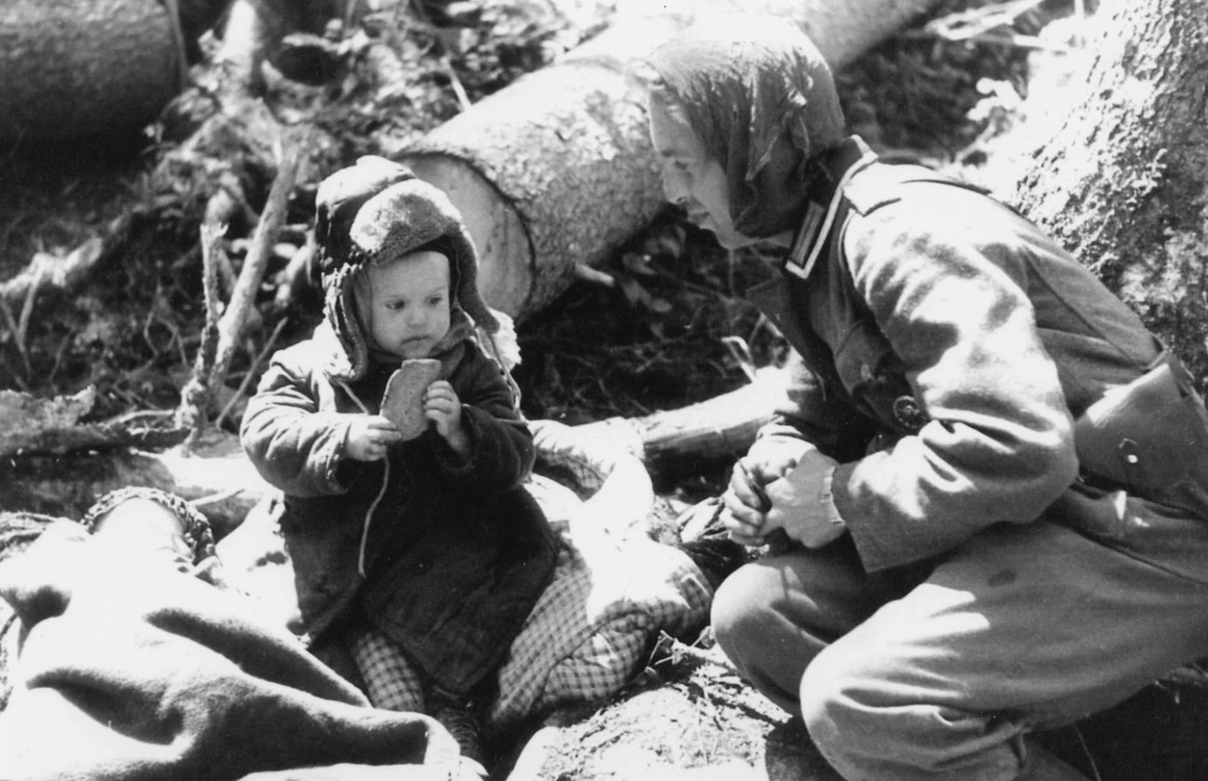 German soldier giving bread to an orphaned Russian boy, 1942. 